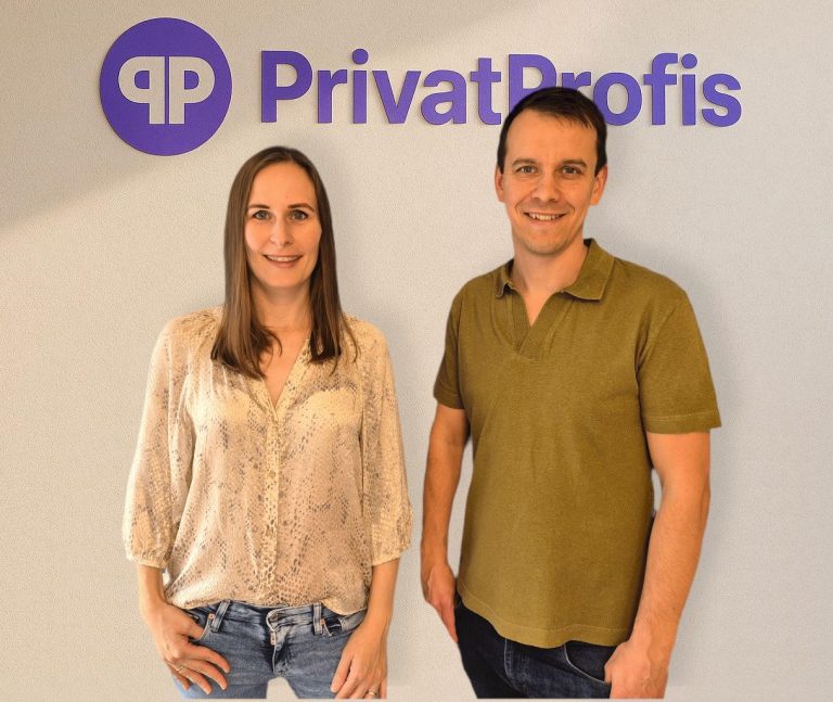 Paar posiert am Ufer eines Gewässers vor einer natürlichen Landschaft.